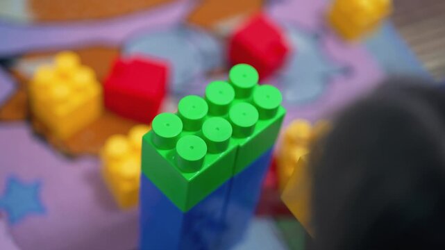 A young child builds with colorful blocks.  Close view child's hands building a tower with colorful interlocking plastic toy blocks. Playground for children. Childhood development and fine motor skill