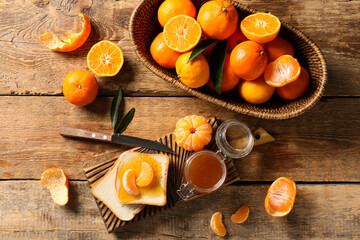 Fototapeta premium Jar of tasty tangerine jam with toasts and knife on wooden background