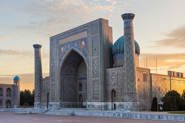 Sher Dor Madrasah grand portal at pastel golden sunrise light – turquoise mosaic tiles, tiger motifs, arched iwan, tall minarets. Architecture masterpiece. Registan Square, Samarkand, Uzbekistan.