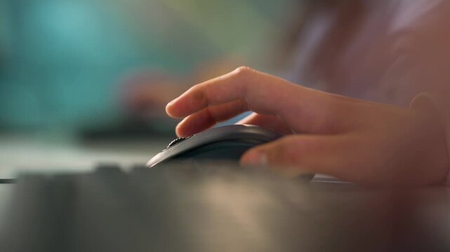Male's hand using mouse, side view. A hand moves over a computer mouse at a desk.  The setting is an office during day time. Businessman or student using laptop at home, online learning, internet mark
