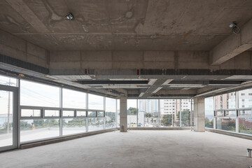 Vacant unfinished building interior with concrete structure and panoramic window wall.