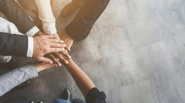 An intimate close-up shot of several business professionals' hands stacked in a powerful display of team unity and shared purpose.