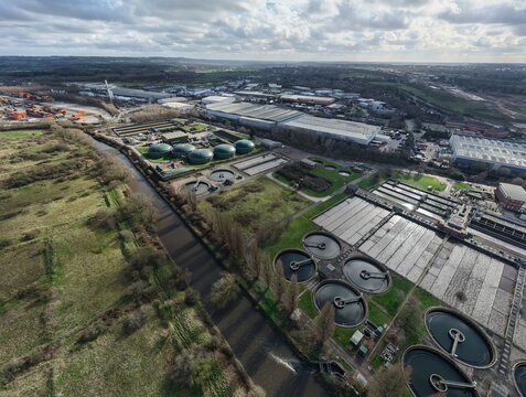 Aerial view of the industrial landscape blending with the River Cole's dark waters contrasting with the green fields, Coleshill, United Kingdom.