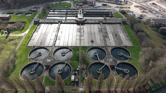 Aerial view of geometric water treatment plant with circular tanks and rectangular settling ponds, Coleshill, United Kingdom.