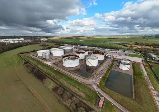 Aerial view of a sprawling industrial landscape where silver tanks gleam under a sky heavy with dramatic clouds, Kingsbury, Tamworth, United Kingdom.