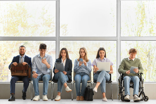 Young job applicants with man in wheelchair waiting for interview at office