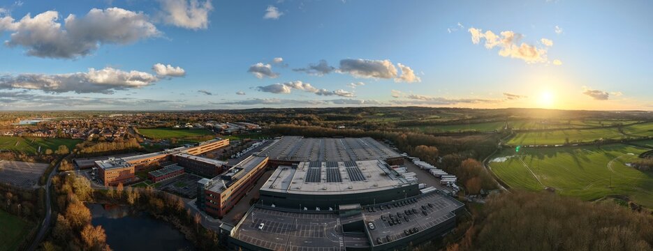 Aerial view of the ALDI UK & Ireland National Head Office, blending industrial architecture with the natural beauty of the surrounding landscape under a golden sunset, Atherstone, United Kingdom.