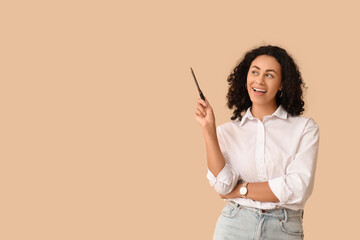 Female African-American job applicant with pen pointing at something on beige background