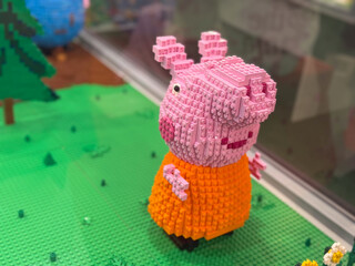 Naklejka premium Mini pig brick sculpture on green baseplate