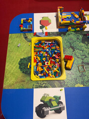 Naklejka premium Colorful building bricks in yellow bin on play mat