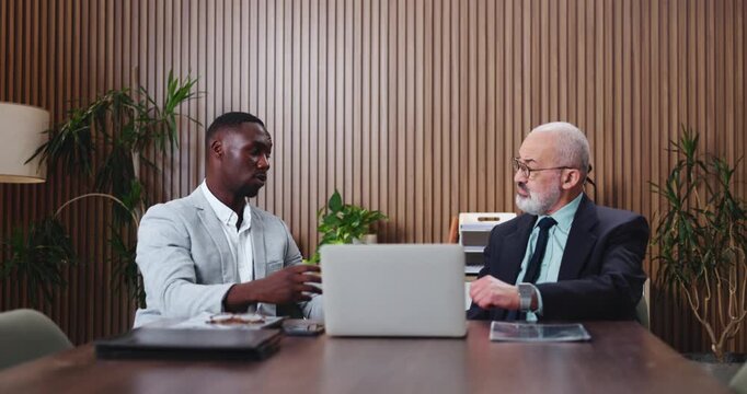 Business, men and meeting with laptop in office for discussion, planning and finance report. People, talking and manager listening with pc, financial briefing and information for investment proposal