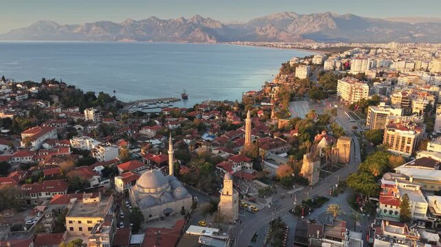 Sunset aerial view of Antalya old town with historic mosques and clock tower, beautiful cityscape of Kaleici district against Taurus mountains. Beautiful Turkish city of Antalya at sunset