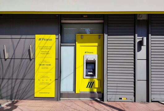 Exterior view of a Piraeus Bank branch, featuring its distinct yellow and grey color scheme. Piraeus is a Greek multinational financial services company with its headquarters in Athens, Greece.