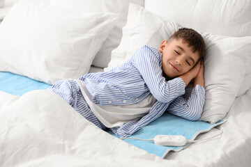 Little boy sleeping on electric heating pad in bedroom © Pixel-Shot