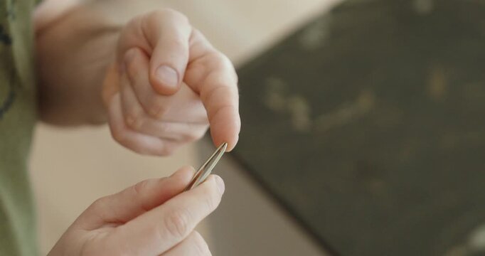 Careful removal of a small splinter from a fingertip using tweezers at home, demonstrating gentle handling, attention to detail, and basic personal care in a calm indoor setting.