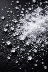 Fototapeta premium Coarse sea salt crystals in varied shapes and sizes, sharply detailed on a dark slate background to highlight texture, contrast, and natural, gourmet seasoning appeal