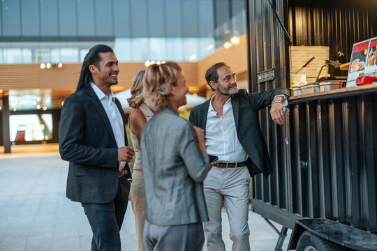 Business colleagues and friends ordering street food together at an outdoor urban food truck in the evening
