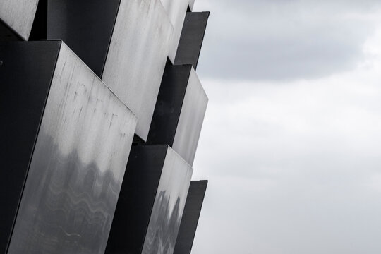 Modern architecture metal facade with abstract geometry angles and grey minimal surface forming a sharp contemporary design with dramatic light