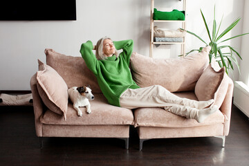 Mindful happy woman homeowner daydreaming in comfortable sofa, sleeping with folded hands behind head, enjoying peaceful relaxation at home © Tatyana Gladskih