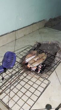 Traditional fish grilling over charcoal fire on simple stove