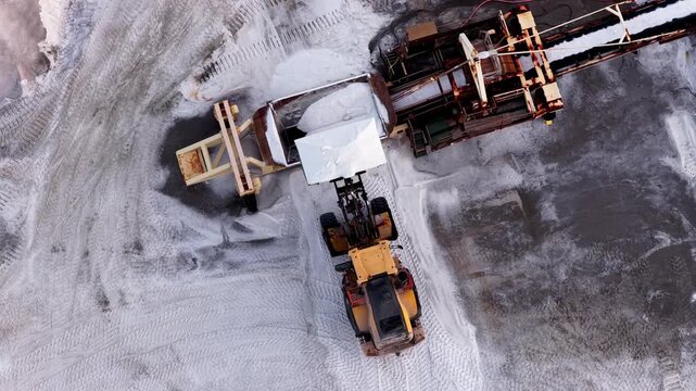 Aerial view of heavy machinery extracting salt, with contrasting textures and tones highlighting the industrial landscape, Aigues-Mortes, Occitanie, France.