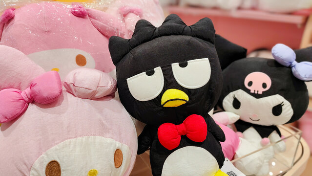 Cute Sanrio character plush toys featuring Badtz Maru with red bow tie sitting between My Melody and Kuromi dolls on December 9, 2025 in Bangkok, Thailand.