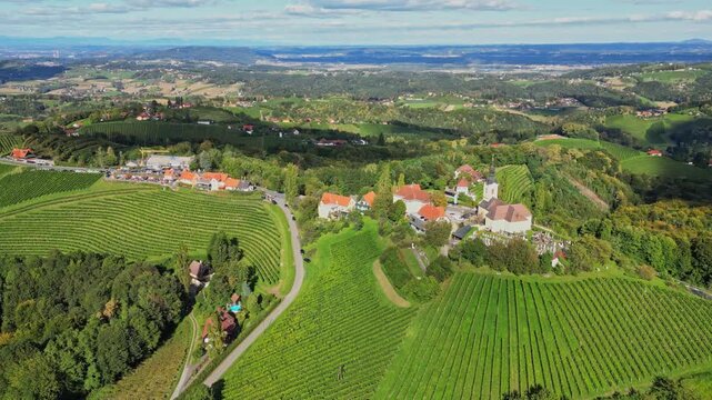 Aerial view of vineyards, buildings, and roads with green hills and valleys creating a scenic landscape, Kitzeck im Sausal, Styria, Austria.
