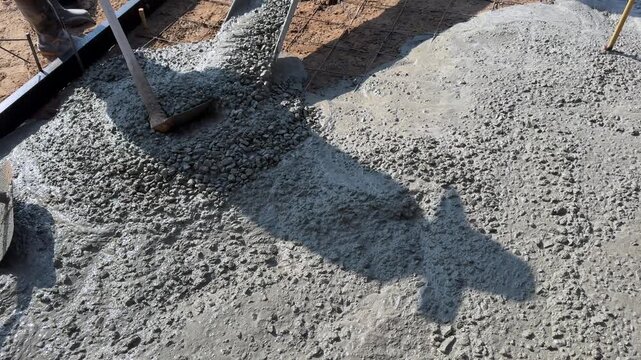 Spreading Wet Concrete with Shovels During Foundation Pour in Slow Motion