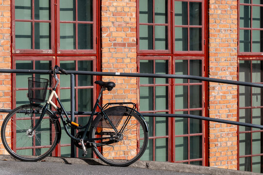 Bicycle for cycling supports urban mobility transport beside brick windows and architecture in Stockholm Sweden on a calm street