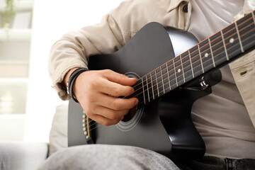 Fototapeta premium Young man playing acoustic guitar at home