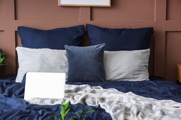 Bed with navy blue linen and laptop in room