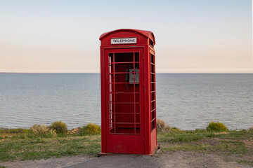 An old red telephone booth on the shore of the Sea of Azov on a May evening. Охуland Park