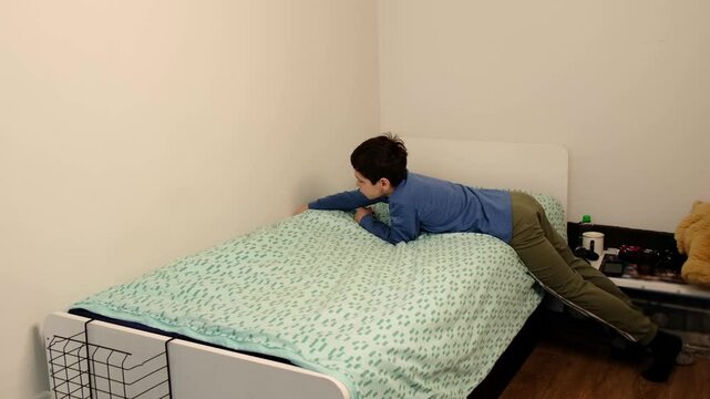 Young child makes the bed, pulling the blanket tight in a quiet bedroom, shot from the side with clean minimal walls. Daily chores support independence, responsibility, and calmer family mornings.