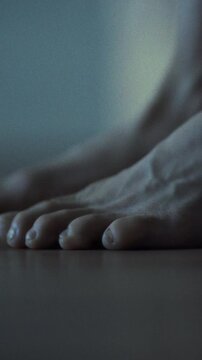 As man slowly rises from bed, his bare feet touch wooden bedroom floor, still heavy with sleep, evoking sense of drowsiness on tranquil morning, marking the gentle transition from rest to wakefulness