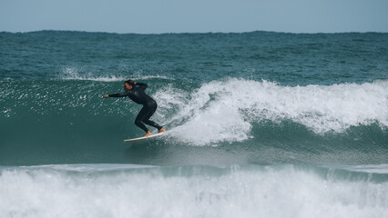 Young man surfing in a wetsuit in the sea on a sunny day