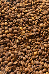 Fototapeta premium Close-up overhead view of roasted coffee beans scattered across a dark surface