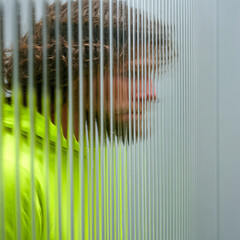 Obraz premium Man looking through textured glass with distorted view