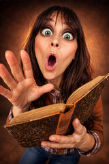 Fototapeta premium Überraschte Frau liest aus einem alten Buch – Ausdruck von Staunen und Neugier