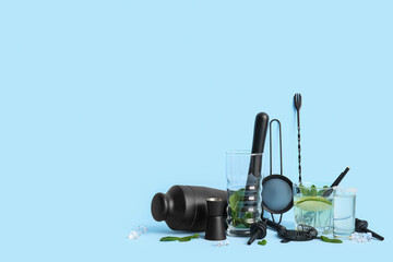 Composition with bartender utensils, glass and shot of tasty cocktails on blue background
