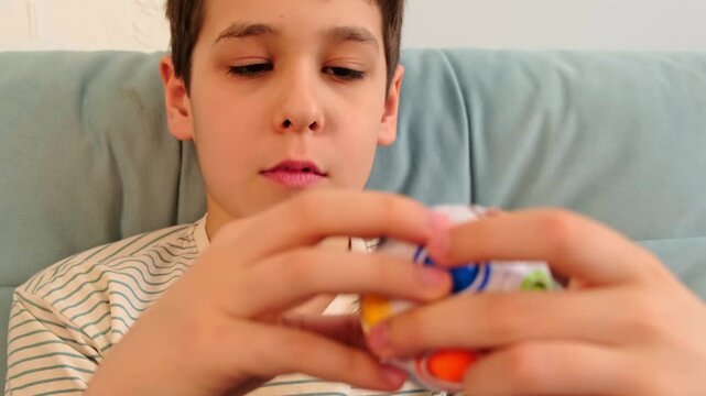 Calm boy turns a multicolor brain teaser toy, close portrait view highlighting hands and focus. Sensory activities improve fine motor control and help replace endless scrolling habits.
