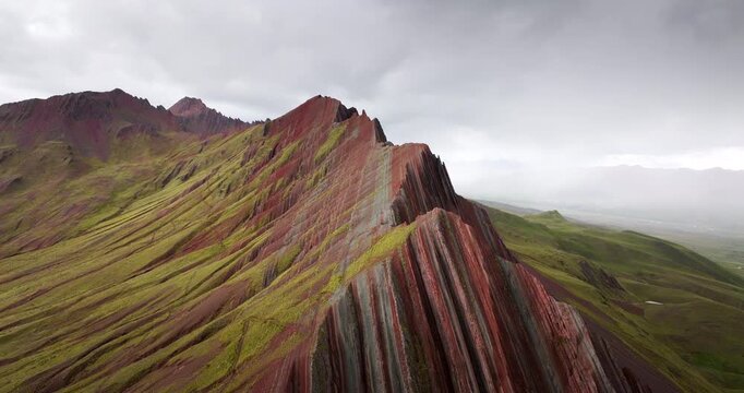 Cinematic aerial view, Pallay Punchu Rainbow Mountain near Layo, Canas Province, Cusco, Peru. Vivid striped ridge and green Andean slopes
