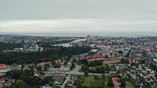 Aerial drone shot of Falkenberg with Atran River flowing through residential neighborhoods and green areas, highlighting urban layout and coastal atmosphere near the shoreline under sky