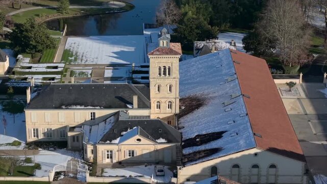 Chateau Lagrange, France - 06 January 2026: Aerial view of Chateau Lagrange Est with snow-dusted rooftops contrasting against the pale stone and landscaped gardens.