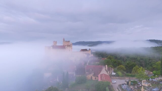 Beynac-et-Cazenac, France - 12 September 2025: Aerial view of Chateau de Beynac shrouded in ethereal fog, its stone walls a silent sentinel against the muted horizon.