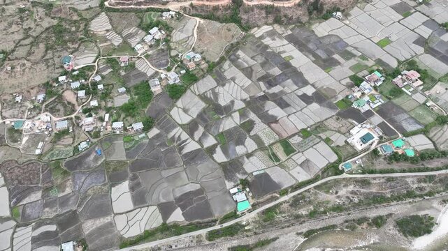 Aerial view of the patchwork fields reflecting the sky near Kyichu Lhakhang, with houses nestled among the greenery, Paro, Bhutan.