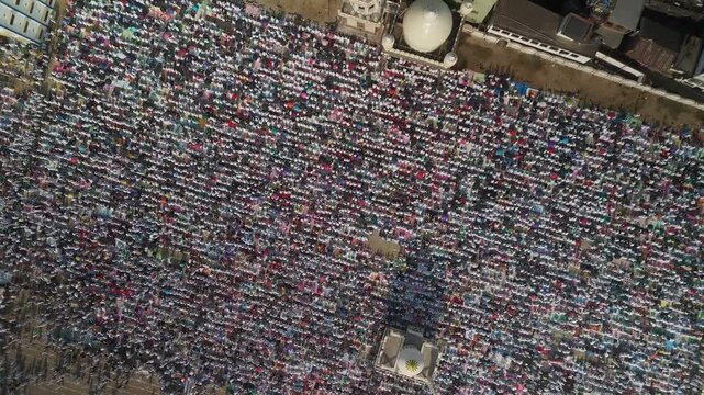 Aerial view of a large gathering of people praying in a field outside a mosque, a captivating scene of unity and devotion, Malda, West Bengal, India.