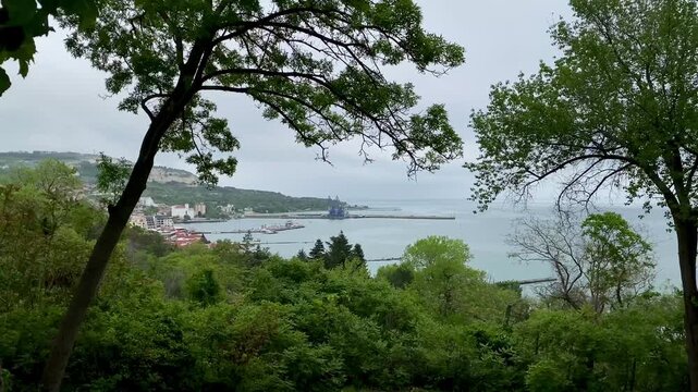 Panoramic view of the city of Balchik, Bulgaria on a cloudy day among trees, foliage and hills. 4k
