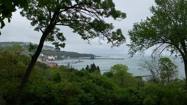 Panoramic view of the city of Balchik, Bulgaria on a cloudy day among trees, foliage and hills. 4k