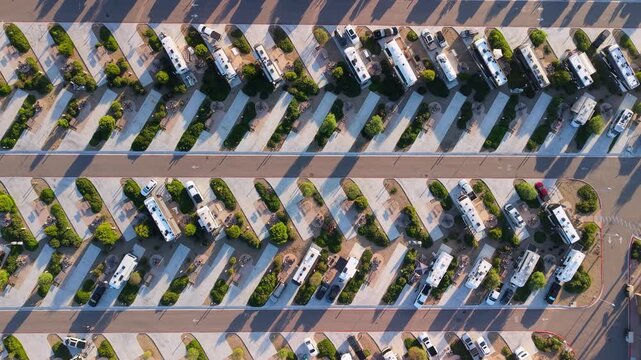 Aerial view of a neatly arranged RV parking lot, showcasing rows of vehicles interspersed with green landscaping and concrete, San Diego, California, United States.