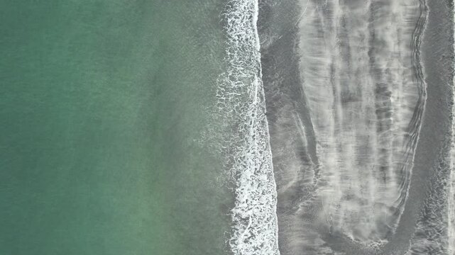 Aerial view of the rugged Isle of Skye coastline where turquoise waters meet dark sandy beaches, creating a stunning contrast, Isle of Skye, Scotland, United Kingdom.